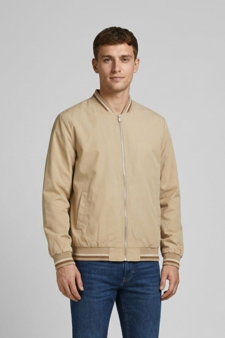 Man wearing the beige bomber half zipped with blue trousers