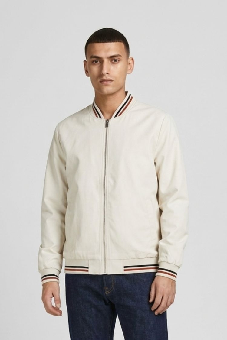 Man wearing the cream bomber over a white tee