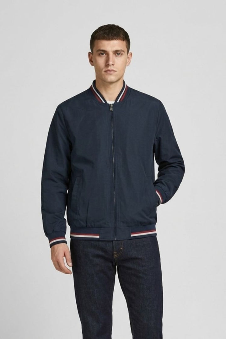 Man wearing the navy bomber zipped up with dark trousers