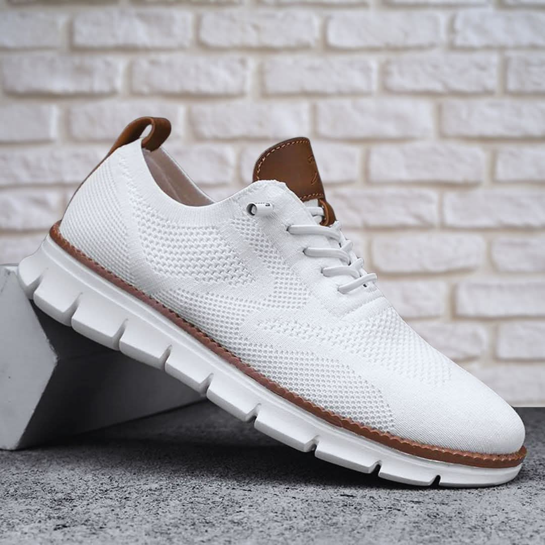 Men's casual trainers in white, knit lace-up shoe with a brown heel tab on a brick backdrop