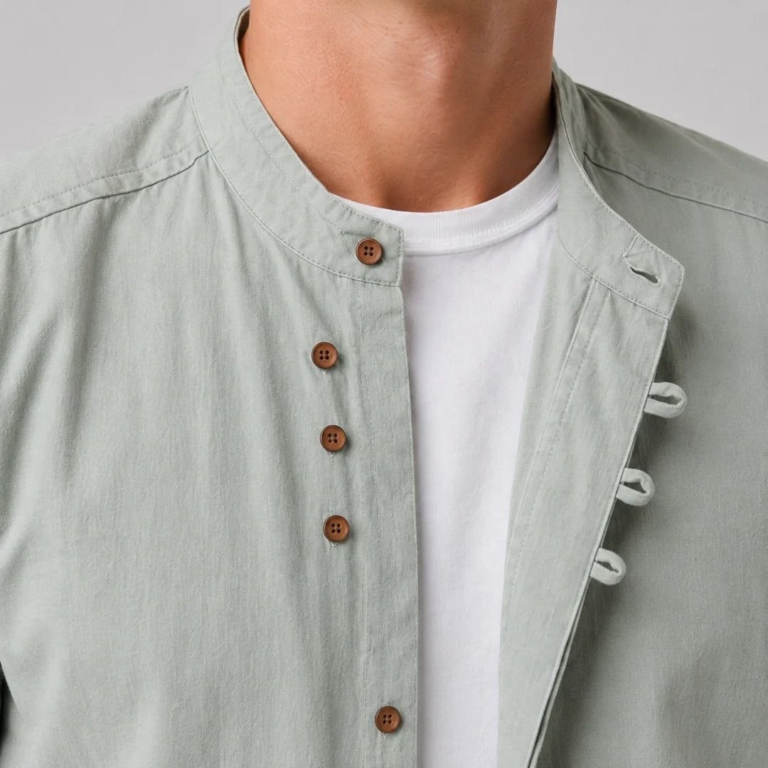 Close-up of the stand-up neckline, brown buttons and fabric loops on a sage green shirt