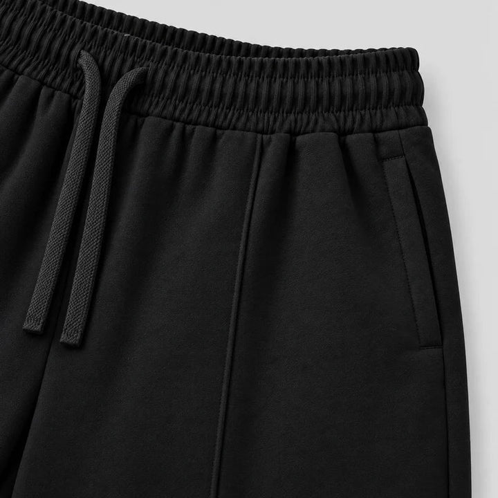 Close up of the elasticated waistband, drawstring and side pocket of the black joggers