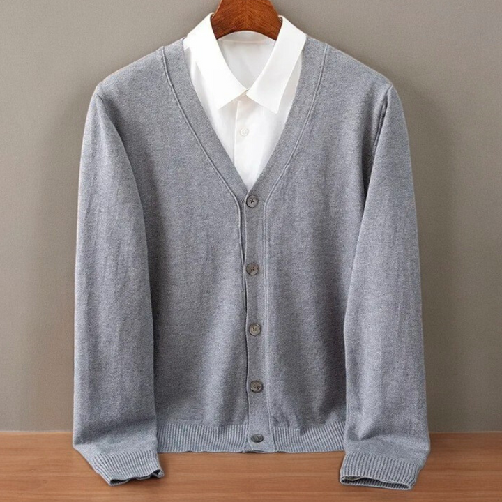Grey V neck cardigan on a hanger over a white shirt