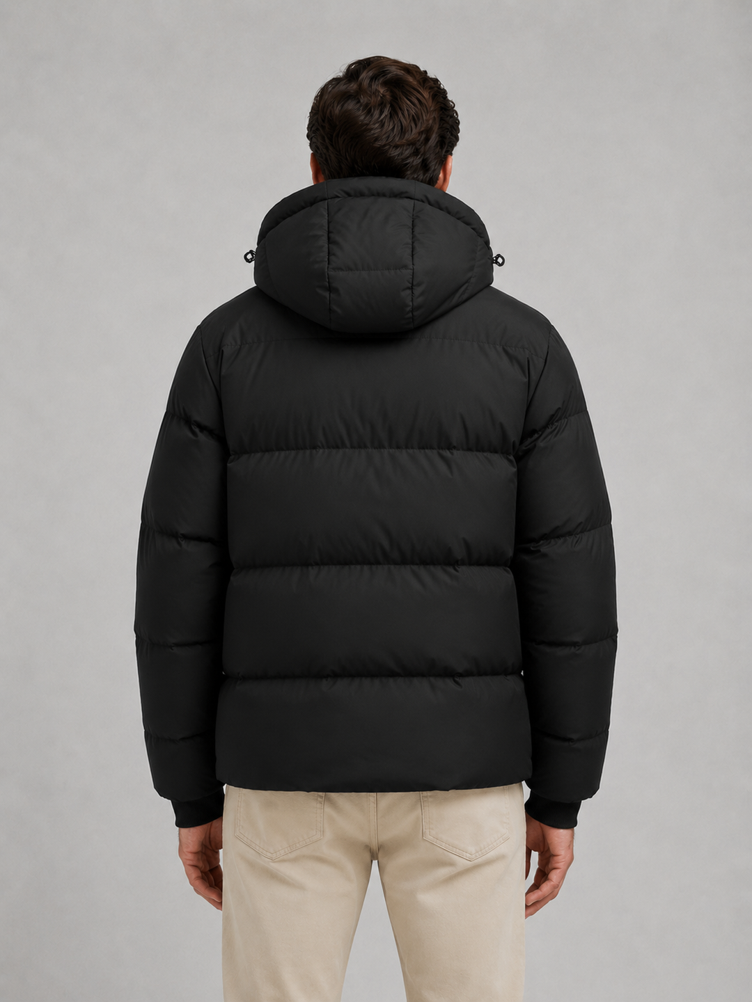 Back view of the black puffer jacket showing the hood and wide quilted channels