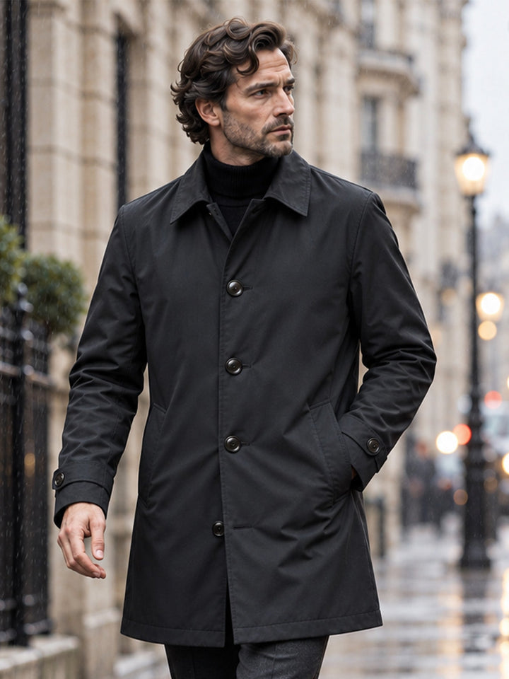 Black single breasted coat with hands in pockets, seen from the front