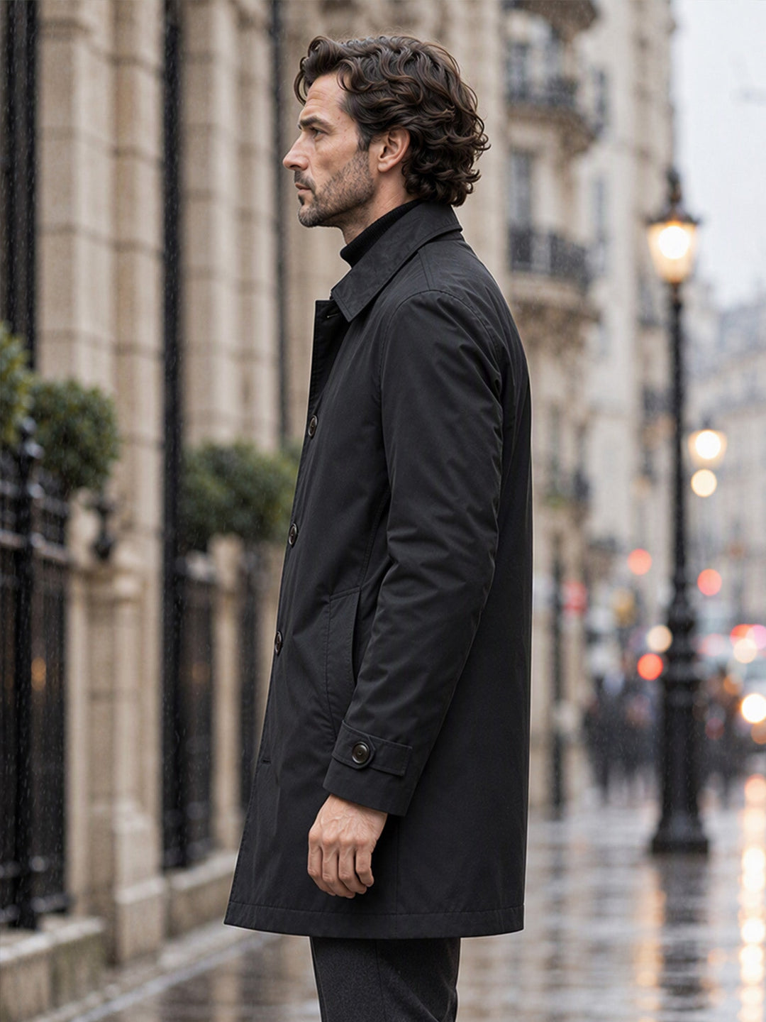 Man in a black mid length coat seen in profile on a city street
