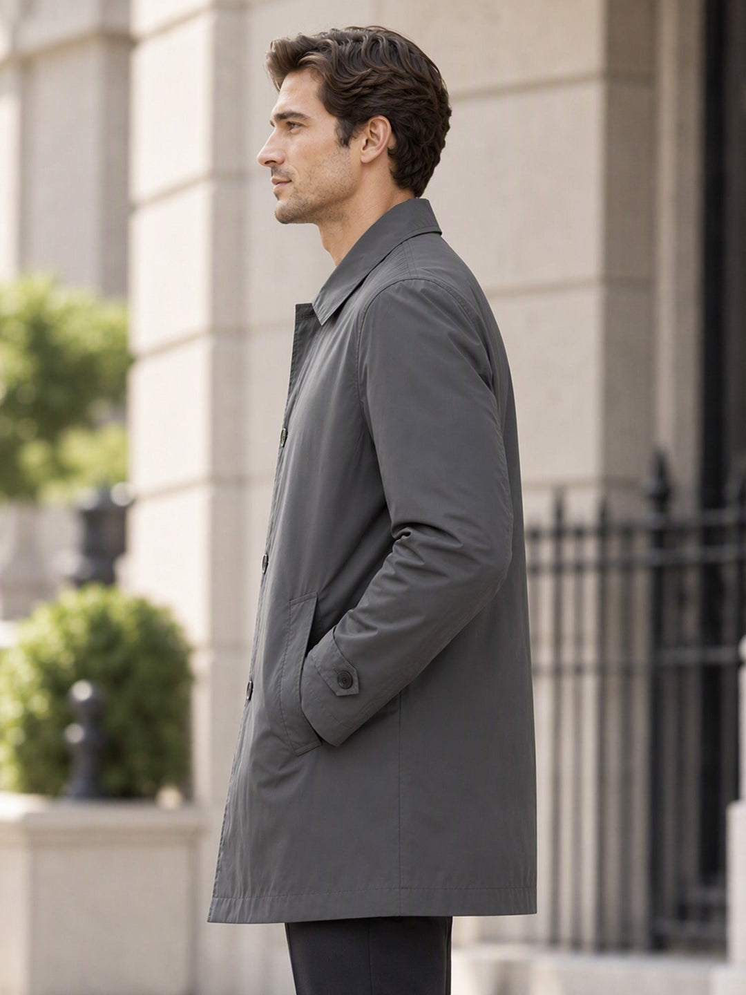 Side view of a grey single breasted coat beside black railings