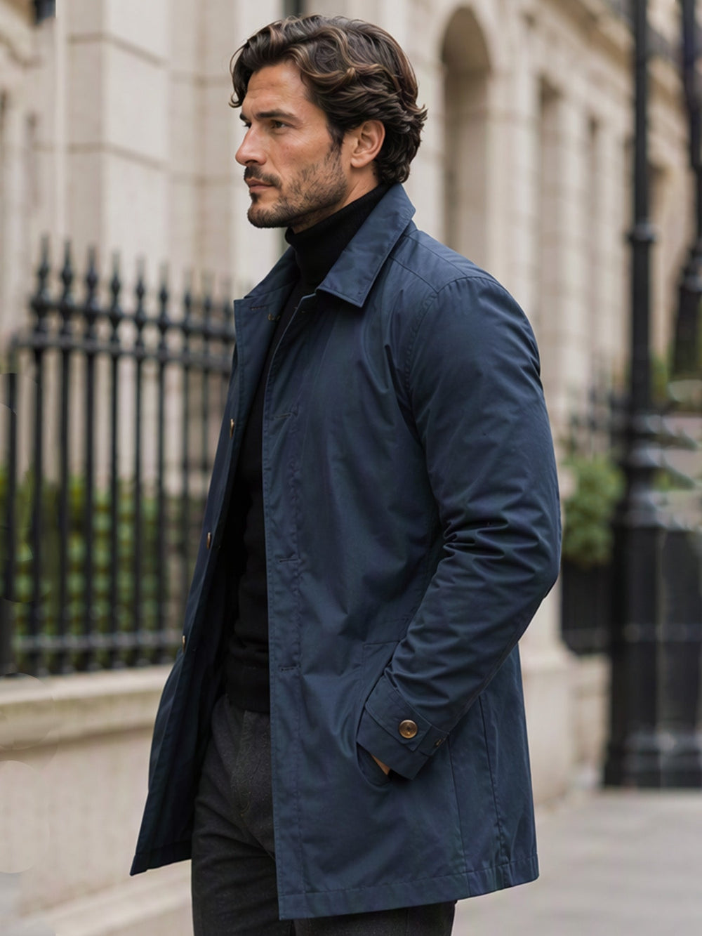 Navy single breasted mac coat with hands in pockets, seen from the front on a city street