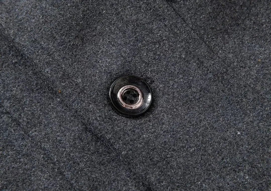 Close view of a black button on the textured grey fabric