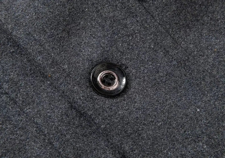 Close view of a black button on the textured grey fabric