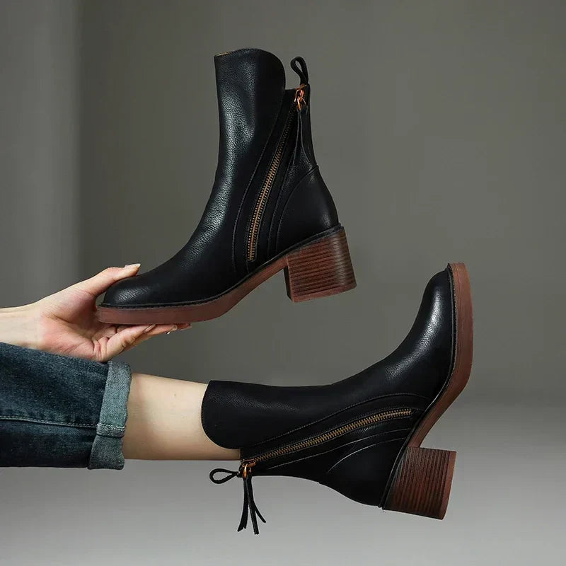 Pair of black boots held up to show the ridged block heel