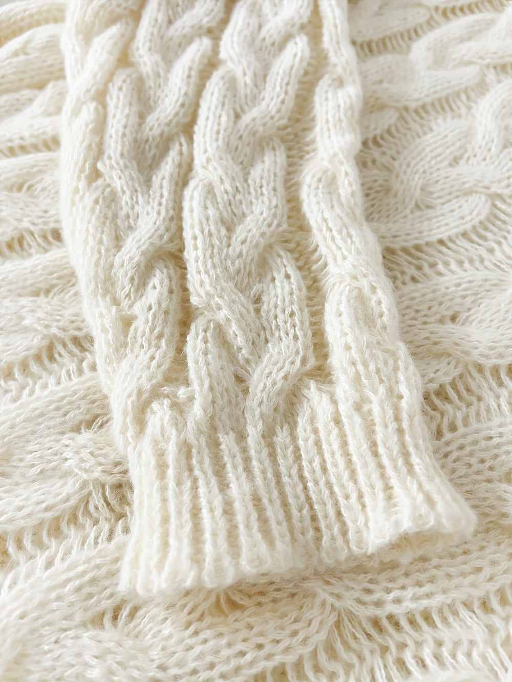 Close up of the cream cable pattern and ribbed sleeve cuff