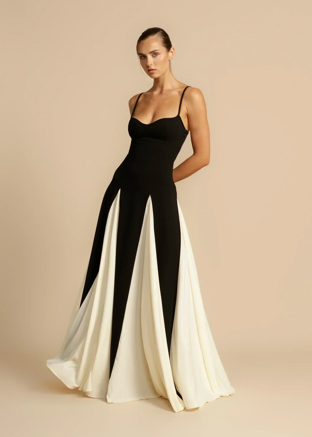 Model turning to show the cream godet panels flaring at the hem