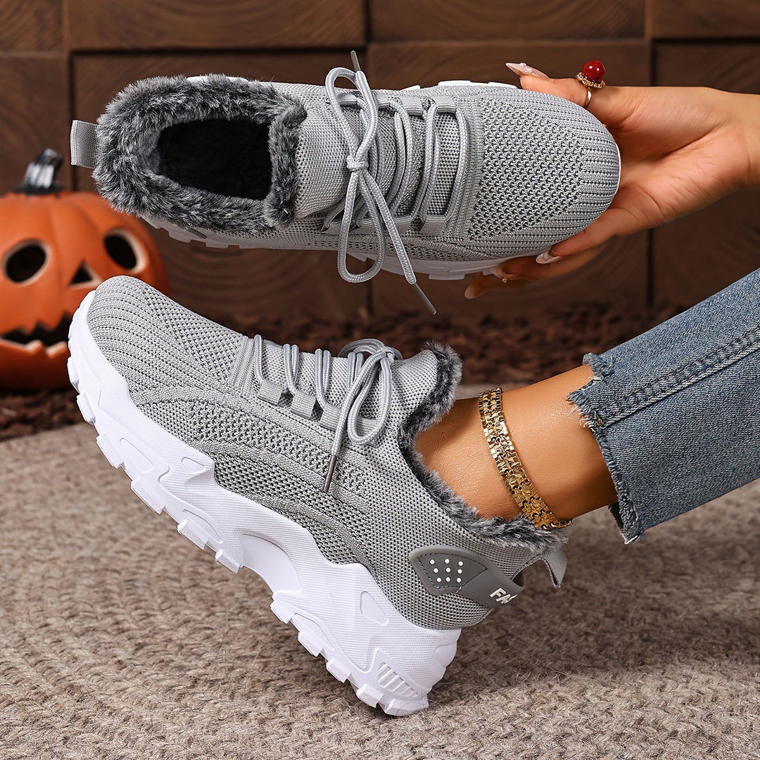 Grey trainers, held up to show the inside and the sole