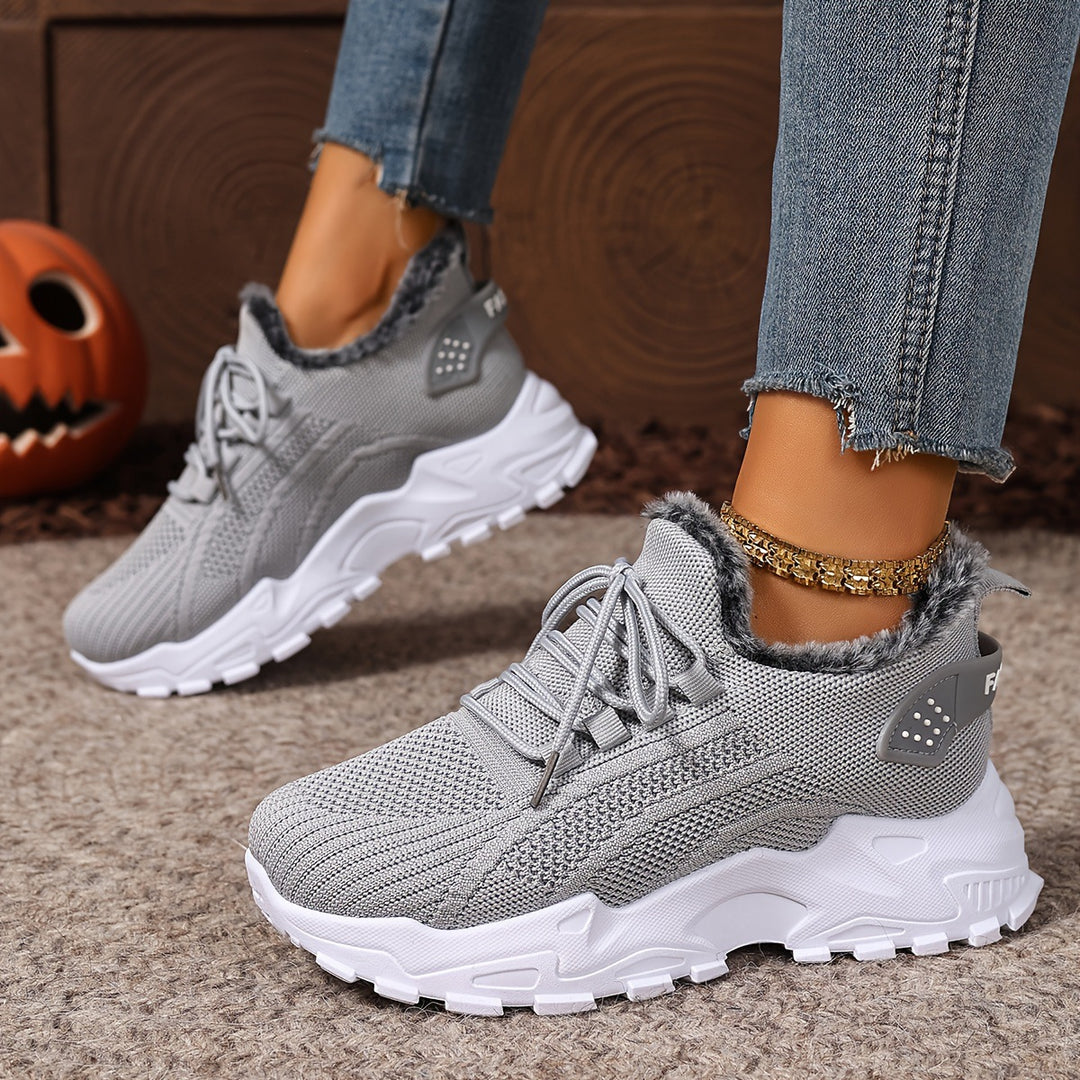 Grey trainers, worn on foot, side view