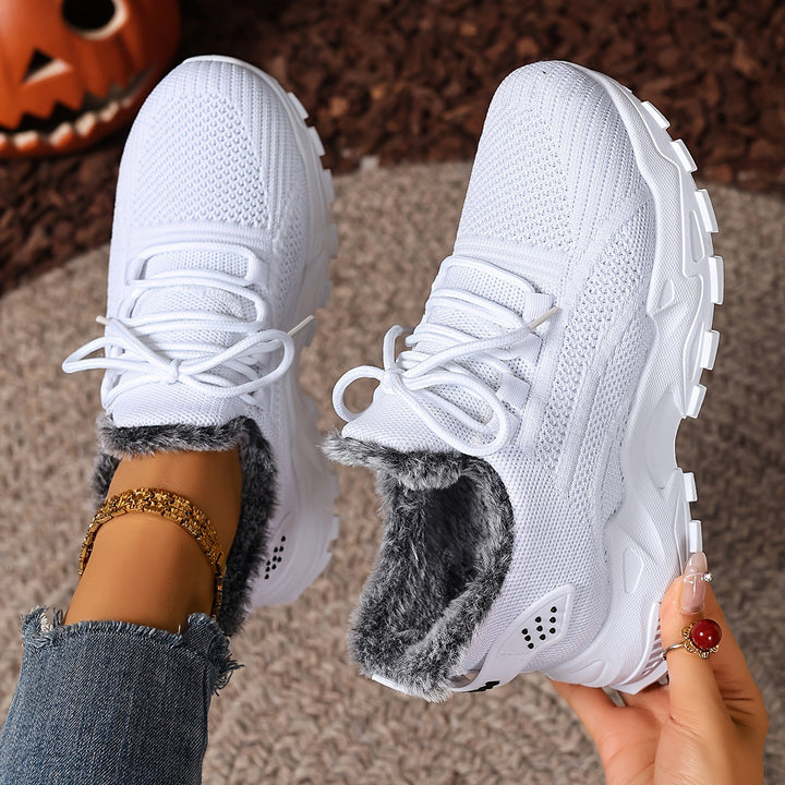 White trainers, held up to show the inside and the sole