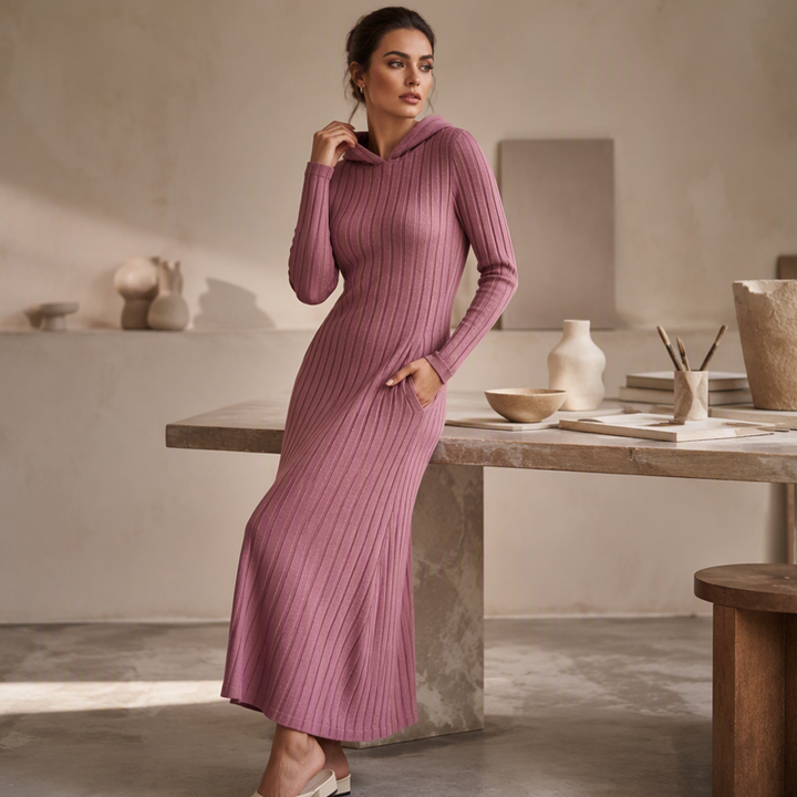 Dusty pink hooded jumper dress with a hand in the pocket beside a marble table