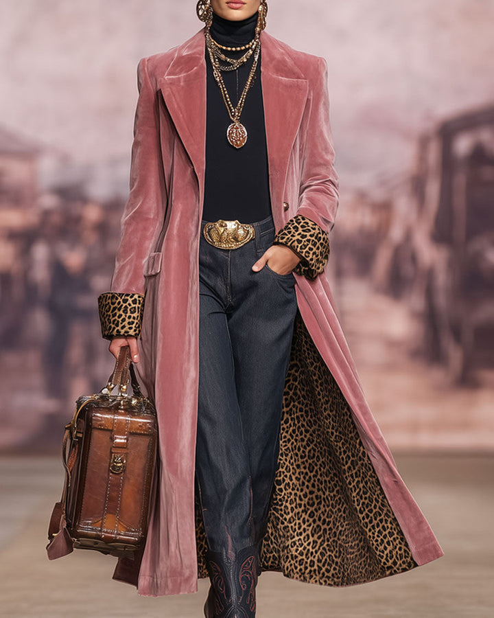 Pink longline tailored coat worn open over a black polo neck and dark trousers