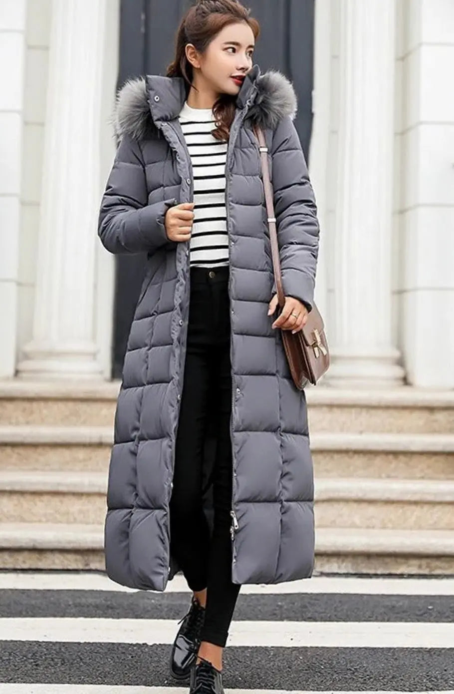 Dark grey quilted long coat worn open over a striped top