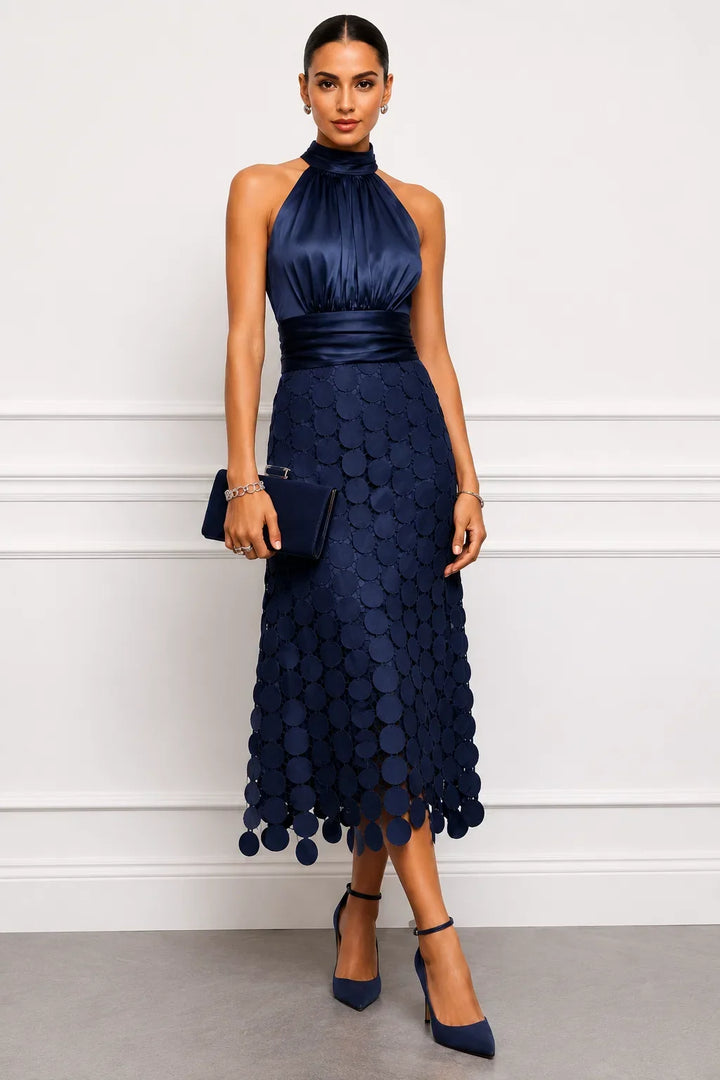 Navy dress with high neck and appliqué skirt worn with matching heels