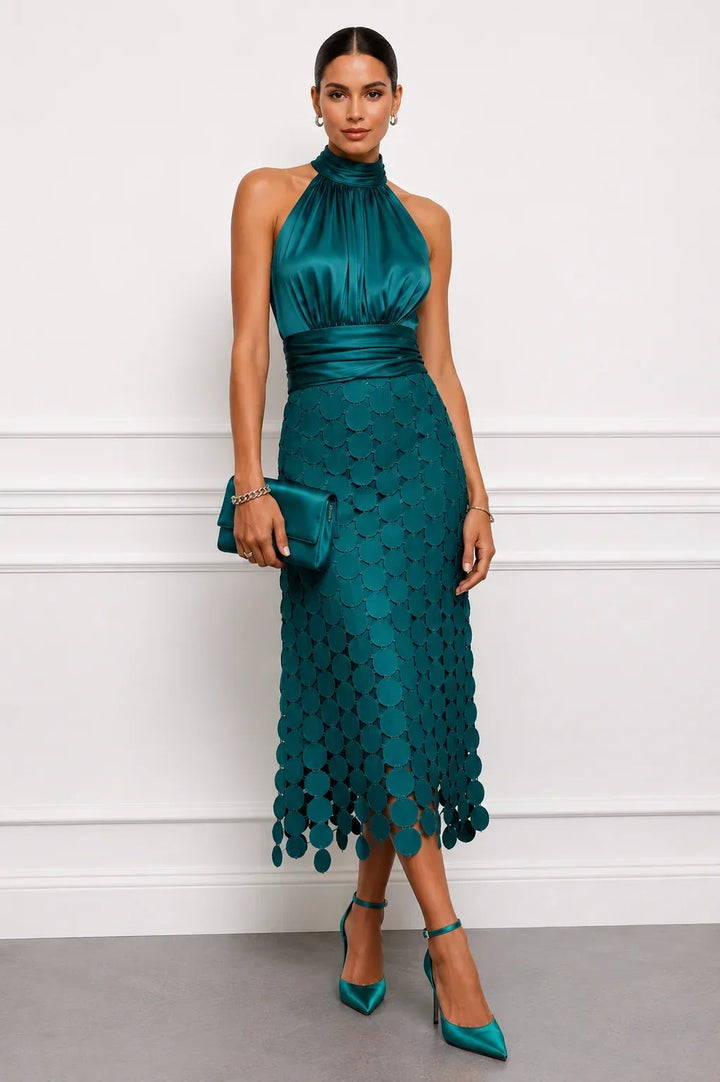 Teal dress with glossy bodice and circle appliqués, styled with a clutch