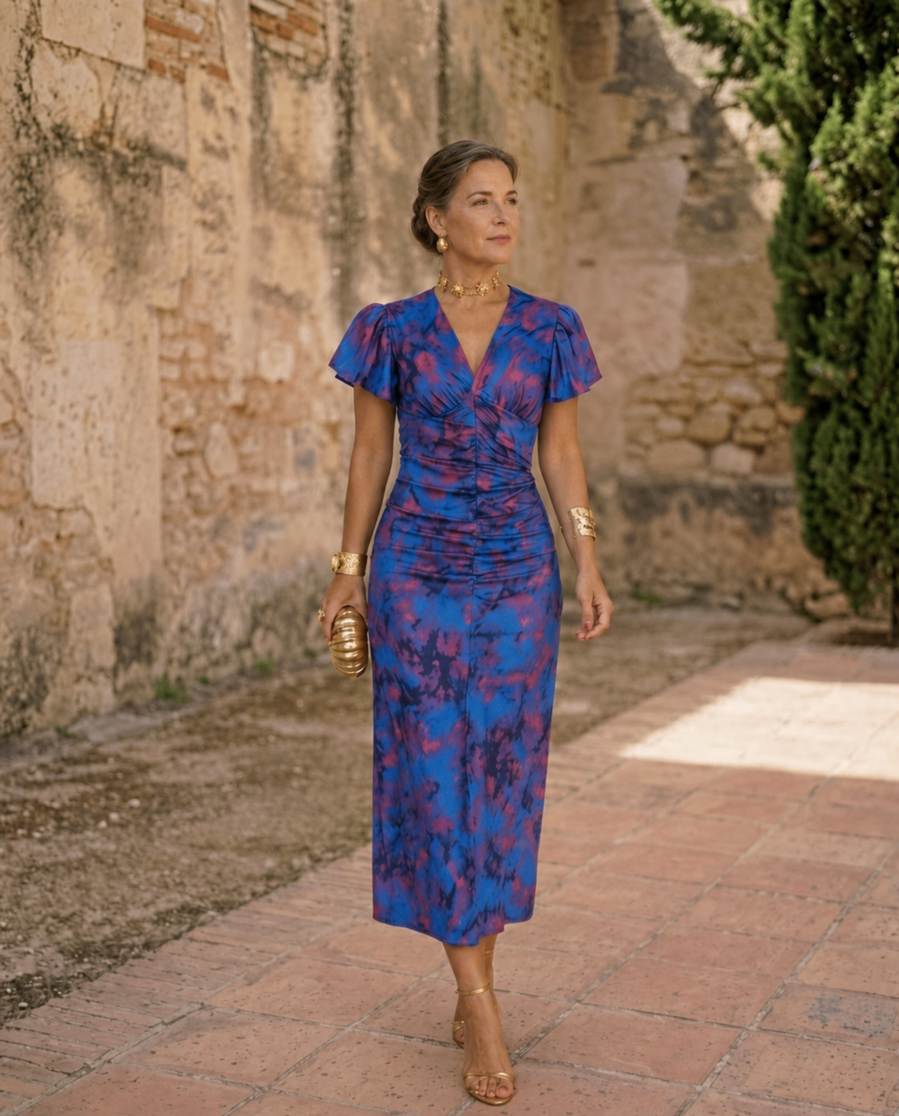 Blue floral midi dress with V neckline and gathered waist worn in a courtyard
