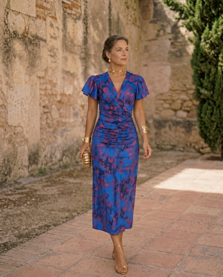 Blue floral midi dress with V neckline and gathered waist worn in a courtyard