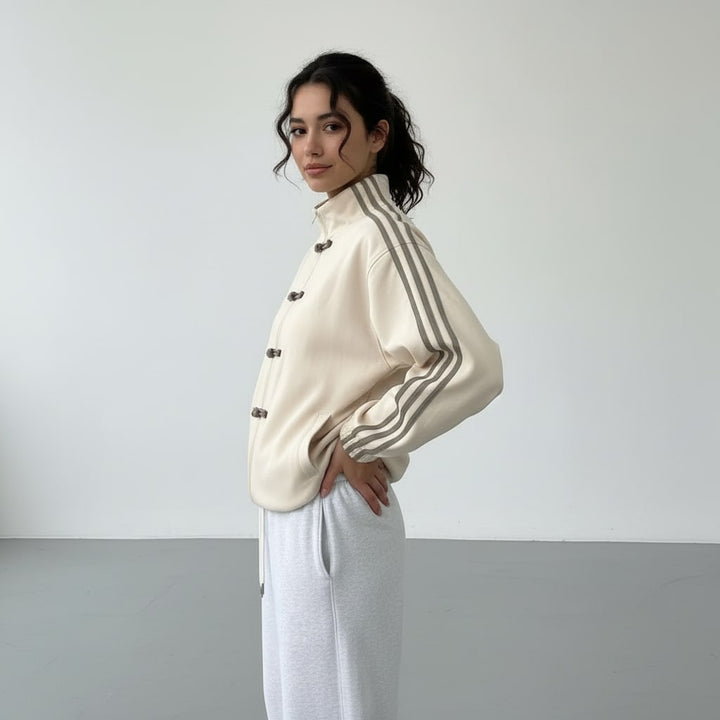 Cream track jacket from the side with a hand on the hip