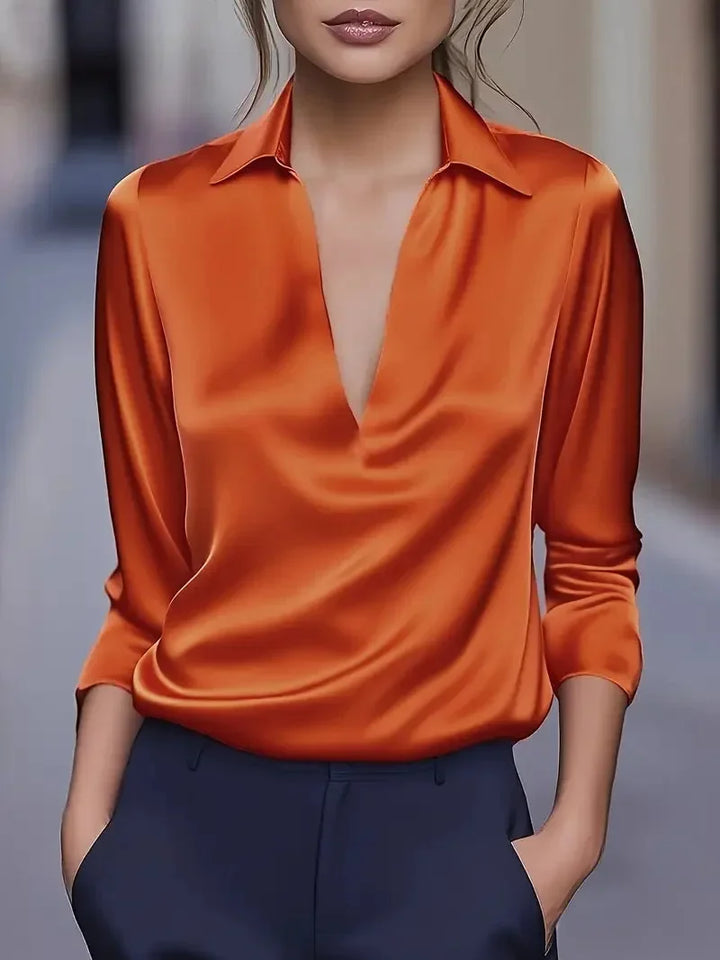 Orange satin-look blouse tucked into navy trousers