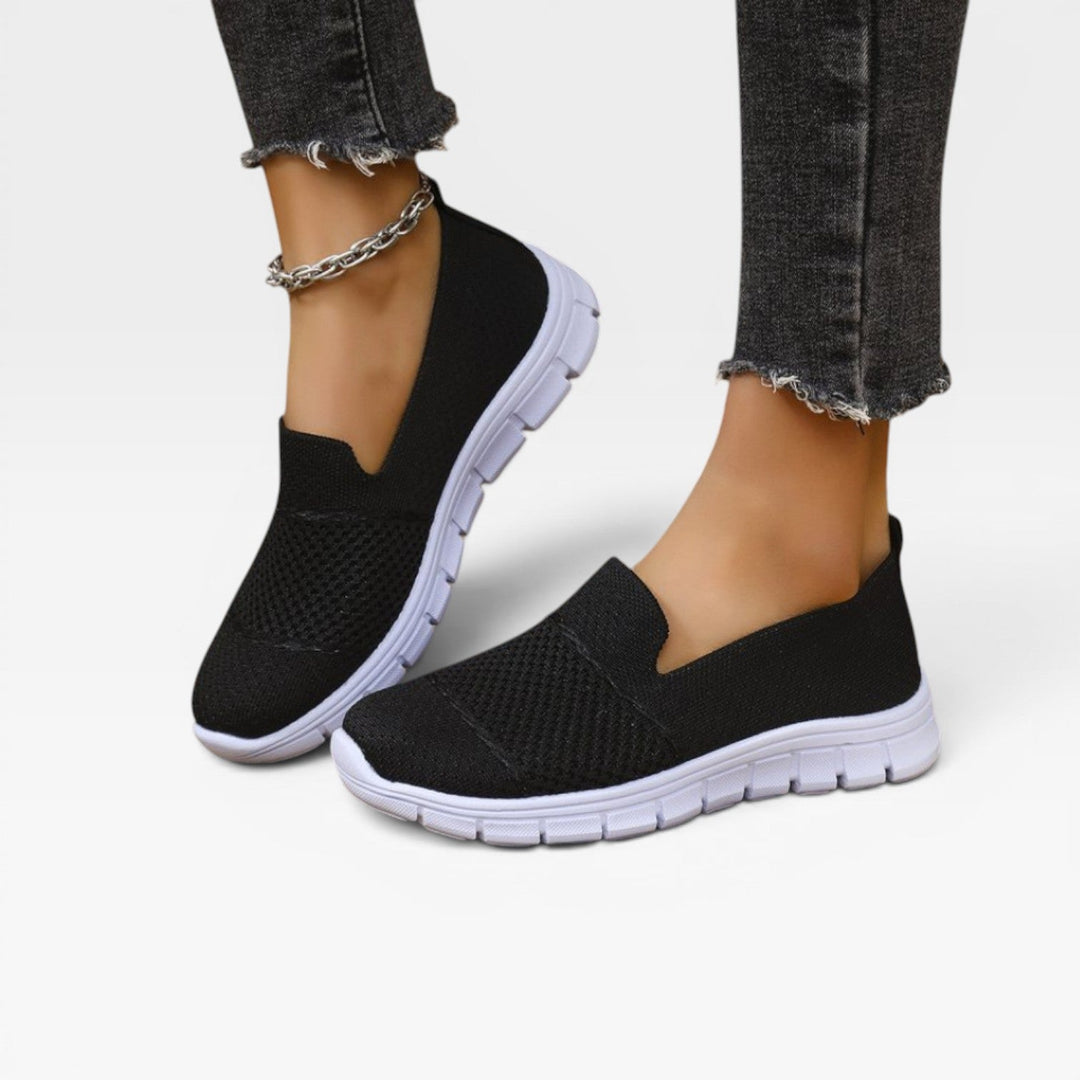 Side view of black knit trainers worn with cropped jeans