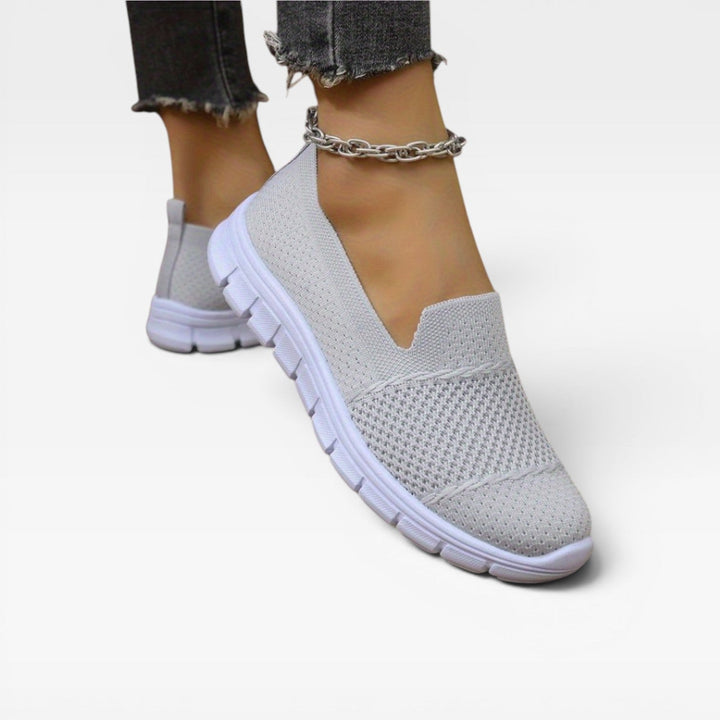 Light grey trainers worn with an ankle chain and frayed jeans