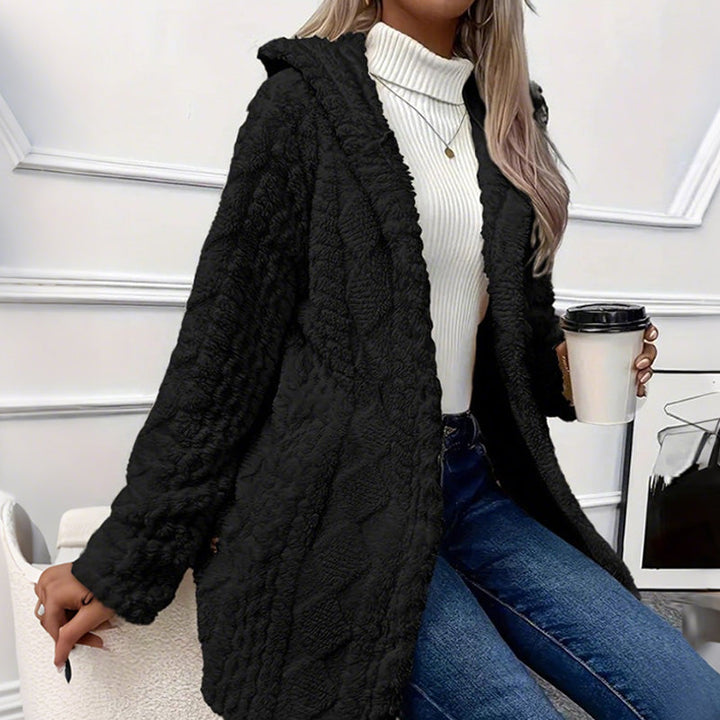 Black hooded teddy coat worn open with blue denim and a coffee cup