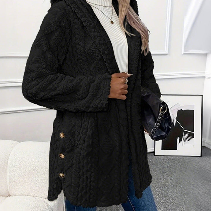 Black coat from the side, mid thigh length with buttons on the hem