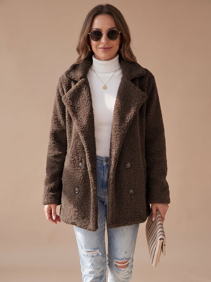 Dark brown teddy coat worn open with sunglasses and a striped clutch