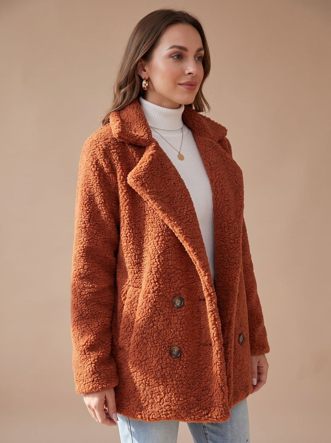 Rust teddy coat seen from a slight angle over a white polo neck