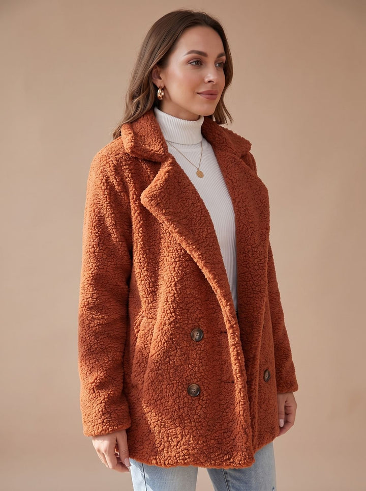 Rust teddy coat seen from a slight angle over a white polo neck