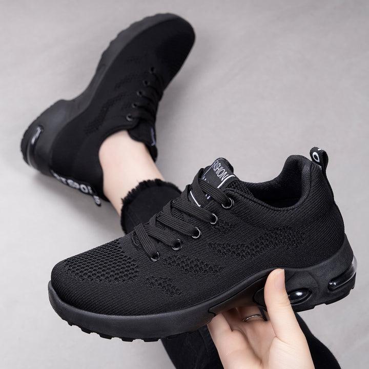 All Black trainers, held up to show the inside and the sole
