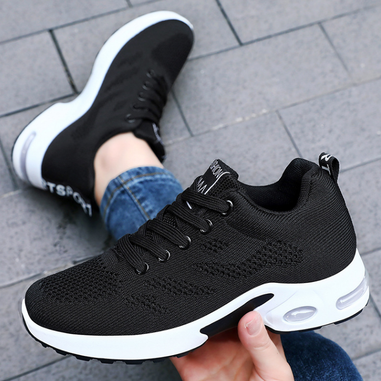 Black trainers, held up to show the inside and the sole