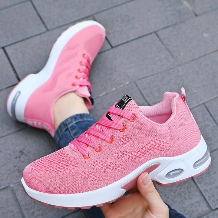 Pink trainers, held up to show the inside and the sole