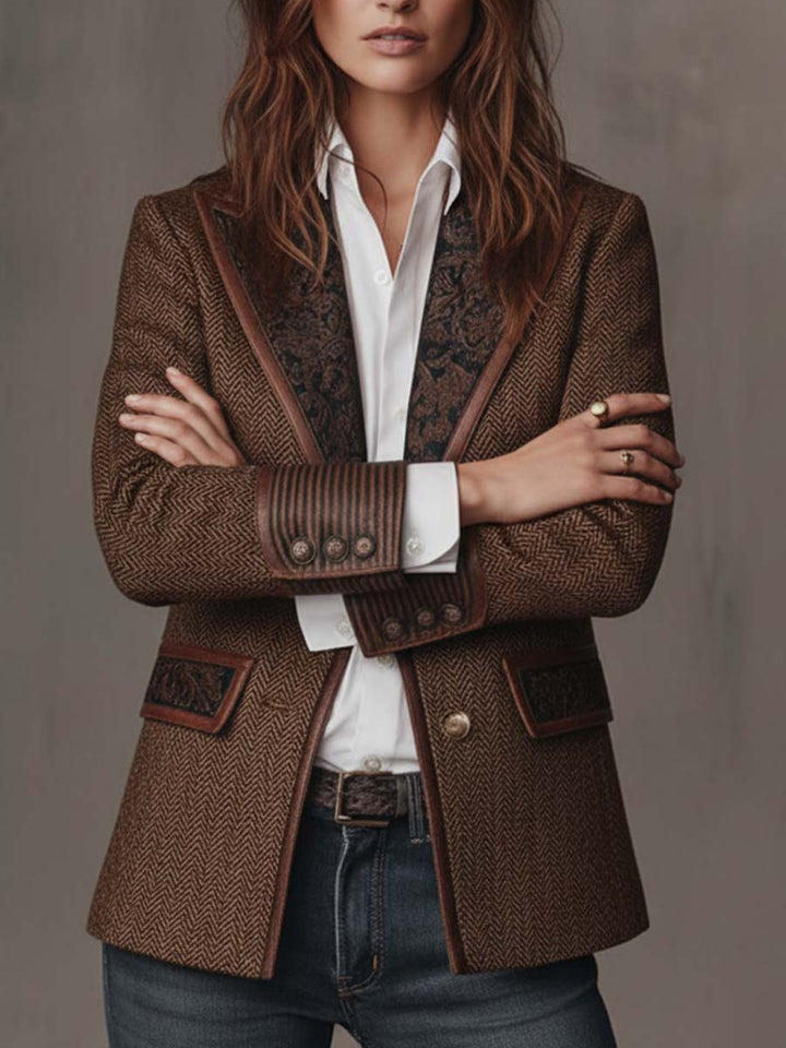 Brown herringbone blazer worn with arms crossed, showing the banded cuffs
