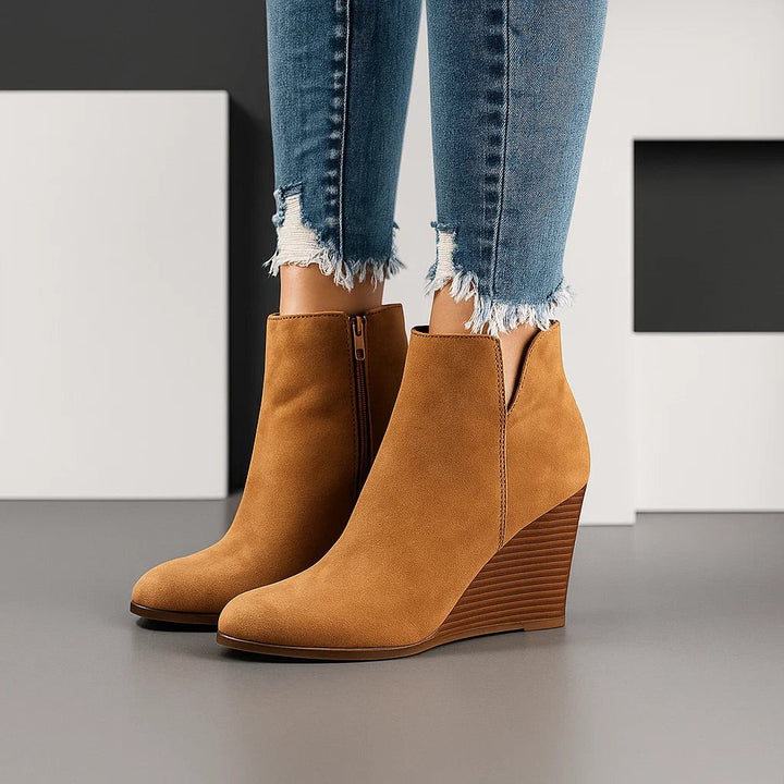 Tan wedge boots worn with cropped frayed trousers in a grey studio