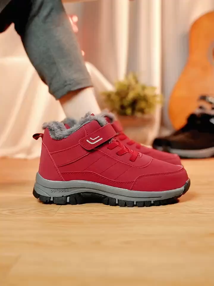 Women's winter boots in red with a touch fastening strap and fleece lined collar on a wooden floor