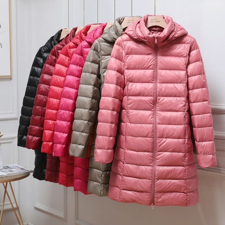 Row of long padded coats in several colours on a rail with a pink coat in front